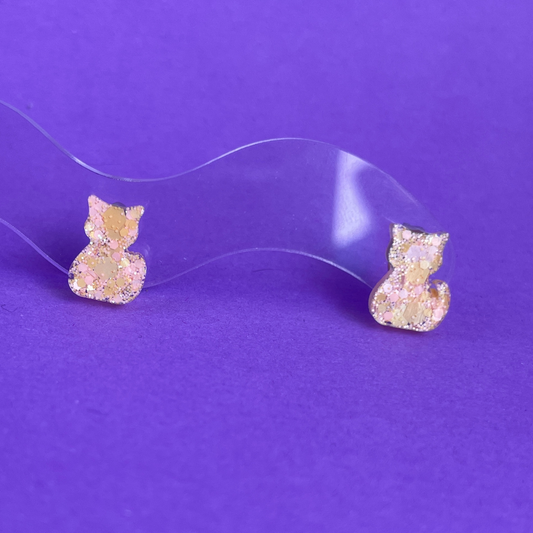 Cat-shaped earrings on a purple background